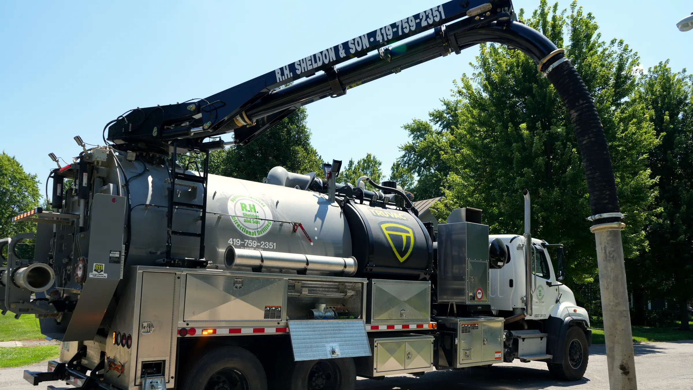 The TrueVac HXX hydro excavation truck with its boom extended and the vacuum hose running down into a dig.